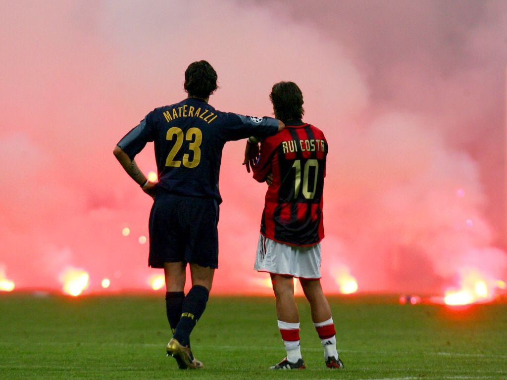 Materazzi e Rui Costa observam pirotecnia que interrompeu dérbi entre Associazione Calcio Milan e Football Club Internazionale Milano.